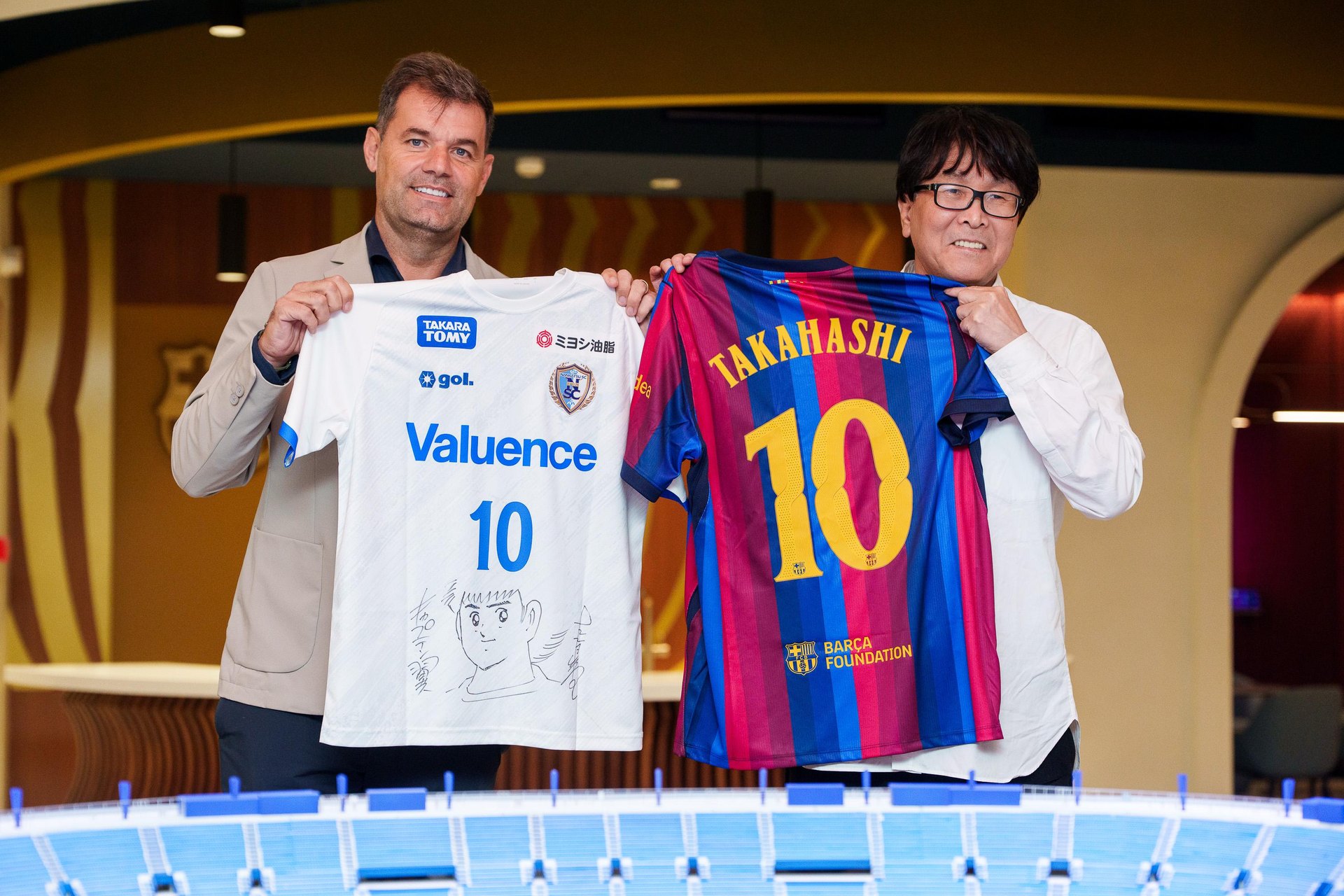 Yoichi Takahashi cầm áo Barça in tên Takahashi số 10 cạnh áo Nankatsu tại Barcelona